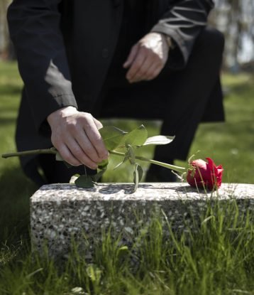 man-bringing-rose-tombstone-cemetery